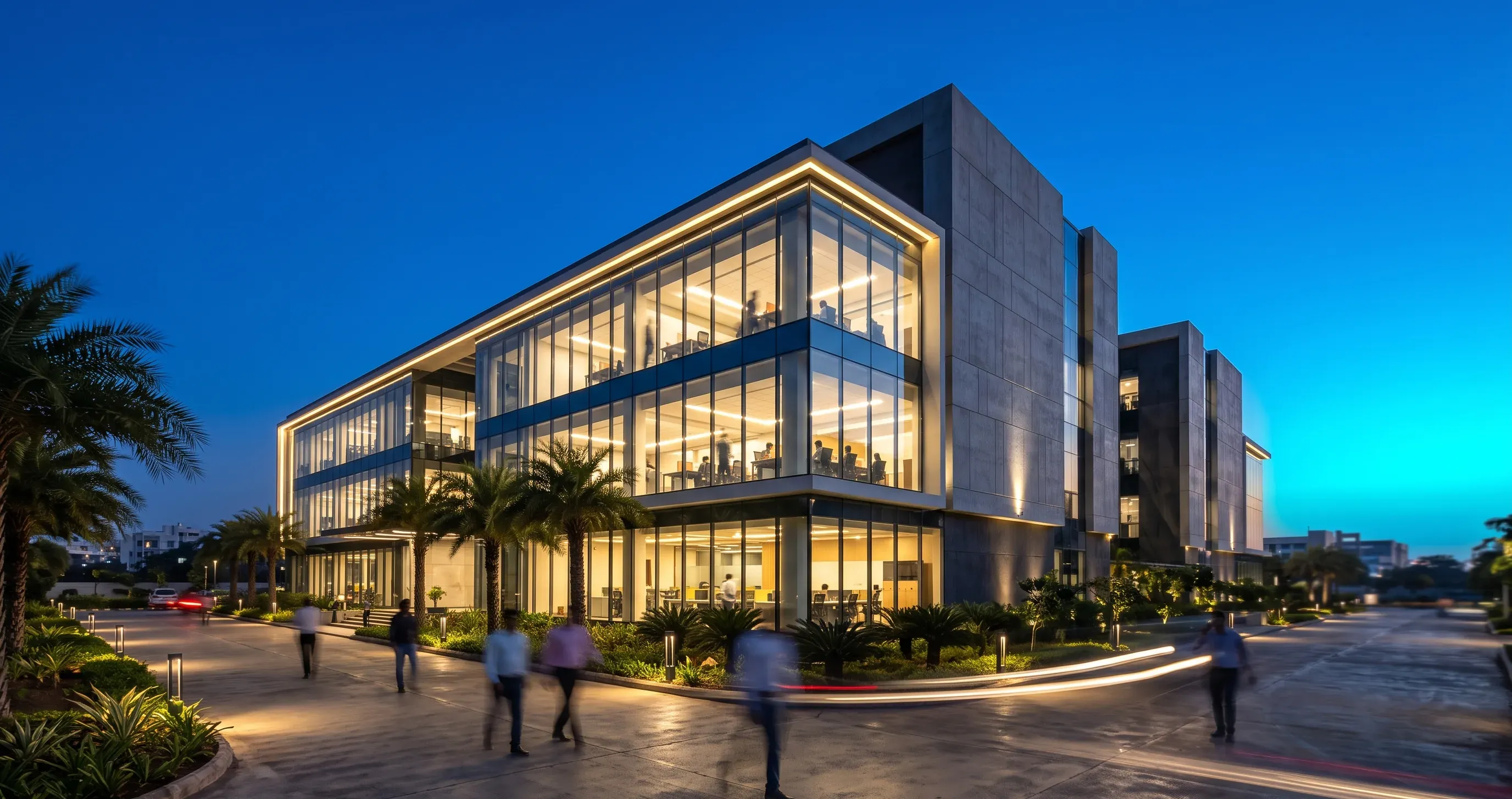 Modern low-rise office in Hinjewadi IT Park, Pune, at blue hour with warmly lit interiors.
